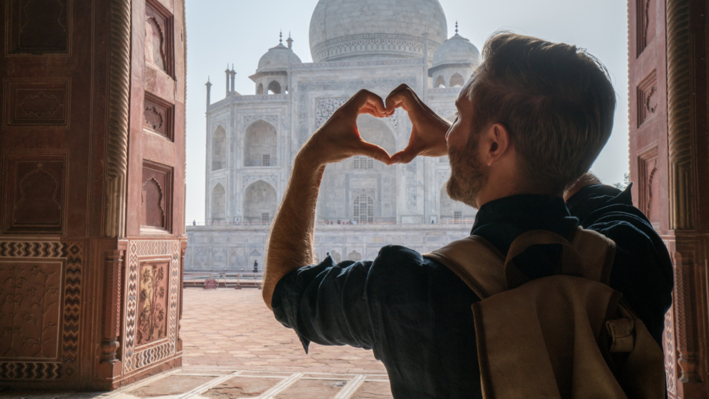 man making a heart symbol with his hands in front of a building