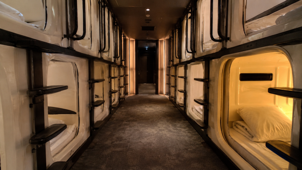 Rows of stacked sleeping pods inside a Japanese capsule hotel corridor
