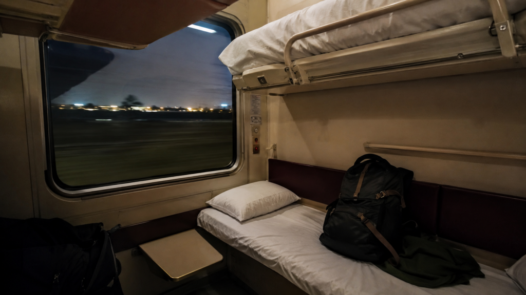 Fold-down bunks and a backpack inside a European sleeper train couchette compartment