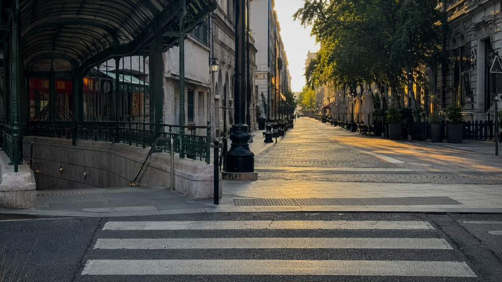 Pedestrian crossing at a city junction with a tram stop on one side and a walking street on the other